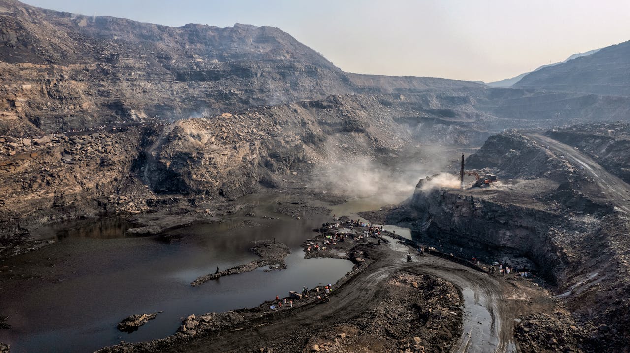 A dramatic aerial view of a coal mine in Dhanbad, Jharkhand, India showcasing rugged landscapes and mining activity.